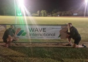 John Morfey and Frederick Mills in front of the Wave International banner during Saturday night lights at the BITS Saints AFL team ground.’